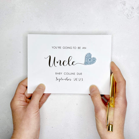A white card with ‘You’re going to be a Uncle’ printed on it. The word ‘Uncle’ appears larger than the rest of the text and it has a little pale blue crochet heart at the end of the word.  Under the word ’Uncle’ is the babies surname and due date making this card a lovely keepsake. 