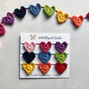 Mini crochet heart bunting comprising of 9 crochet hearts. Colours are Pale pink, Bright pink, Purple, Navy Blue, Light Blue, Lime green, Yellow, Orange and Red. The string of hearts have been wound on a small piece of card - ready for gifting. 