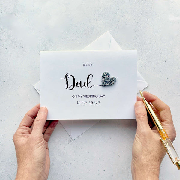 A white card with 'to my Dad on my wedding day' printed in black text. The wedding date is also on there too. The word 'Dad' is much larger than the rest of the text. There is a grey crochet heart coming off the 'd' in 'Dad'.