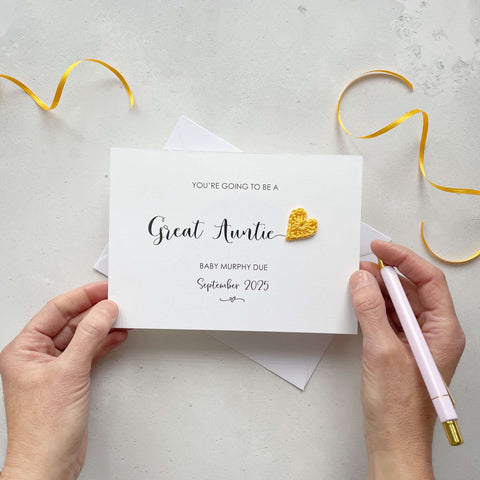 A landscape pregnancy announcement card with the text “You’re going to be a Great Auntie” in elegant black font. Below, it says “Baby Murphy due September 2025,” with a small decorative flourish. The card features a small crocheted yellow heart.